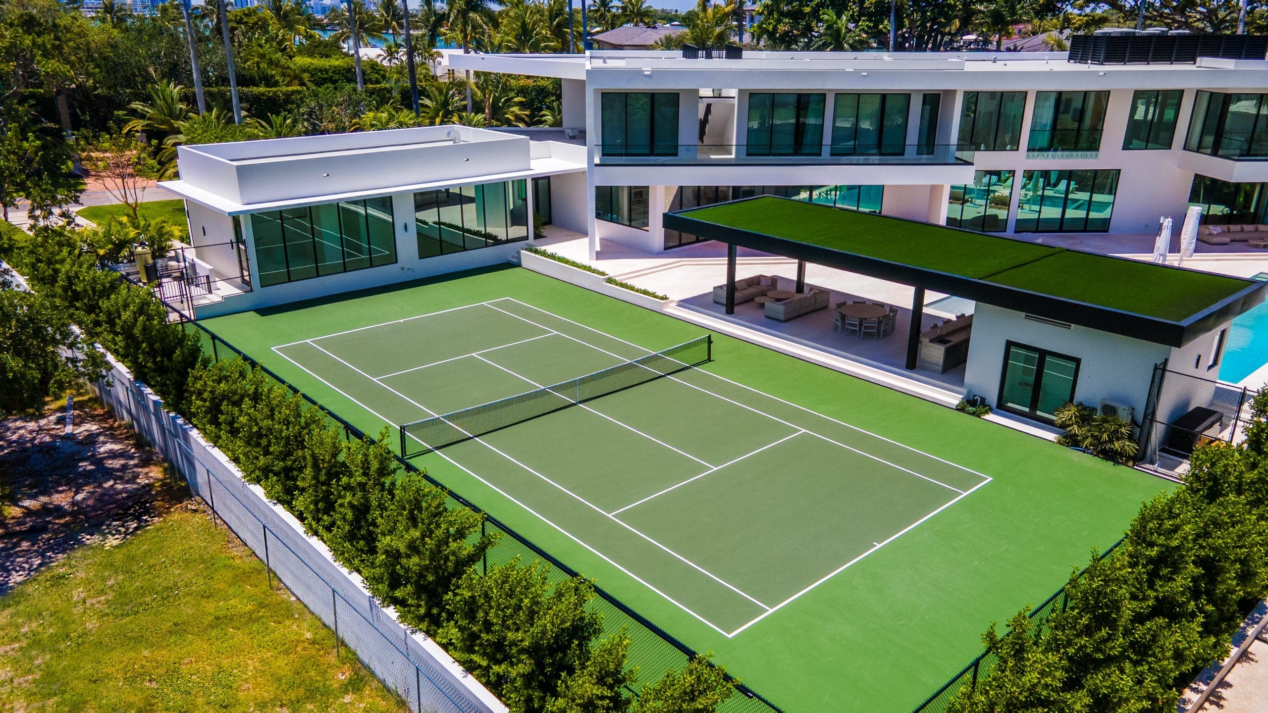 Green private tennis court beside a modern luxury home