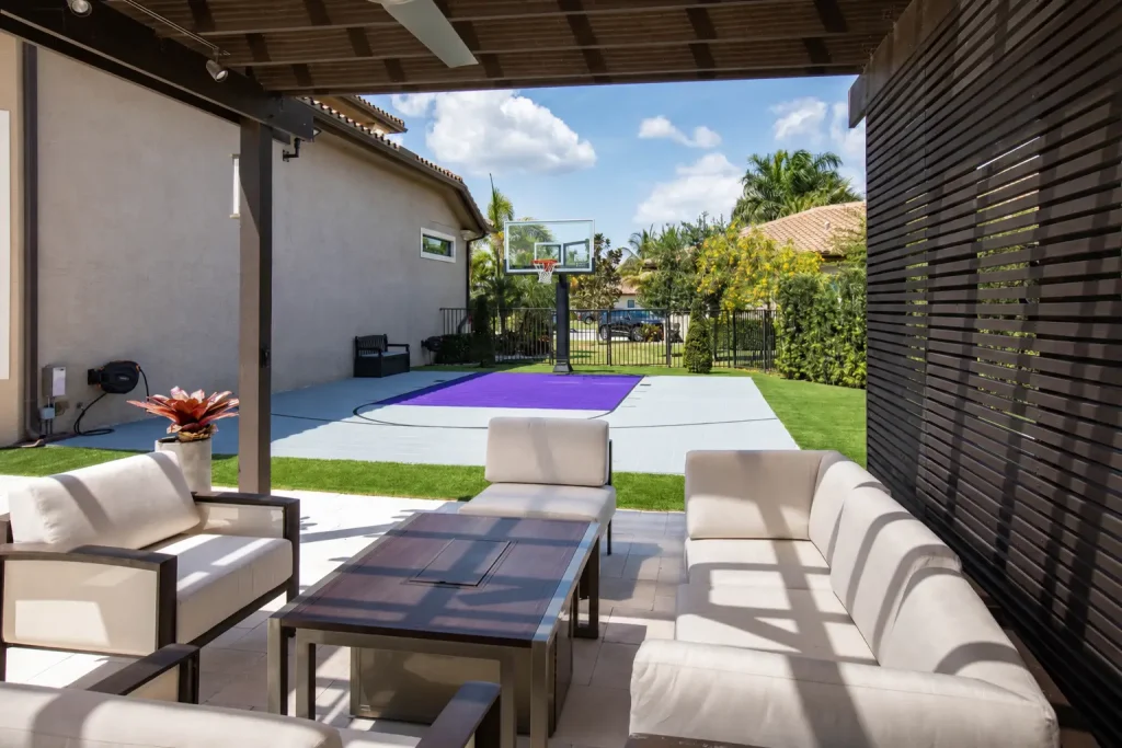 Gray backyard basketball court with a purple key viewed from a covered outdoor patio